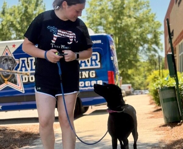 trainer walking black dog