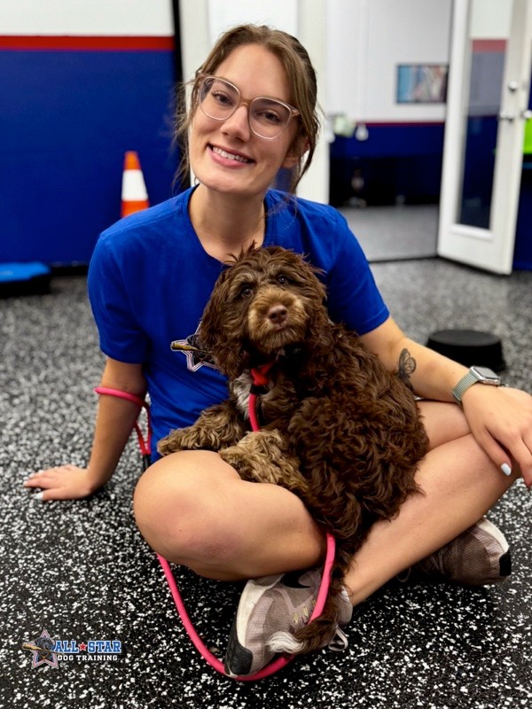 All-Star Dog Training employee sitting with dog in lap