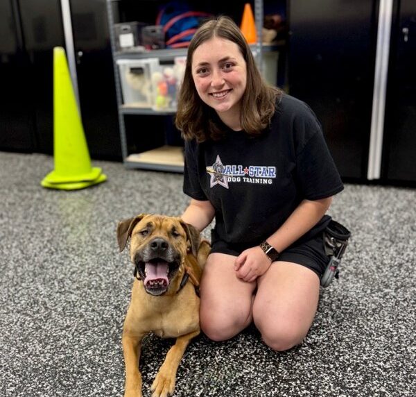 All-star dog trainer sitting on floor posing with dog